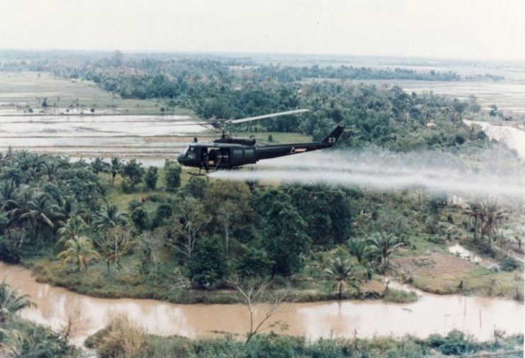 U.S. Army Huey helicopter spraying Agent Orange over agricultural land during the Vietnam War