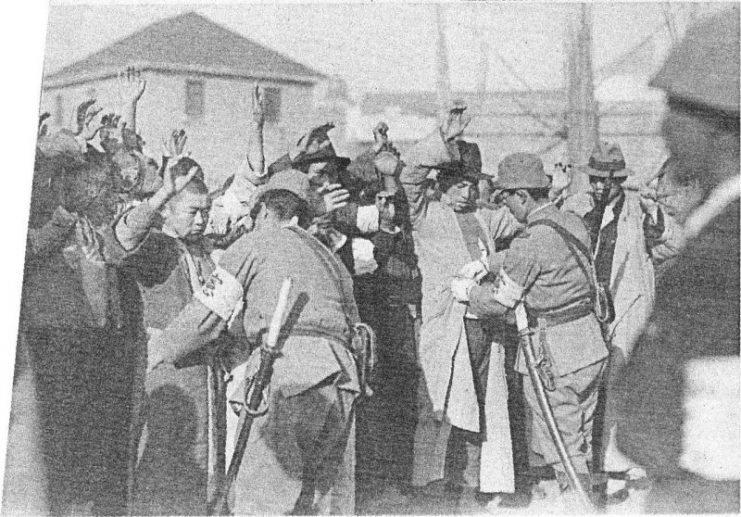 Japanese soldiers searching Chinese men for weapons