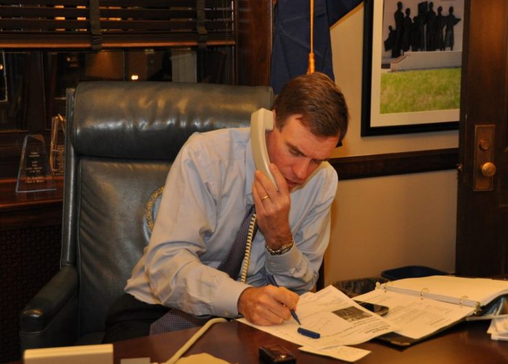 Senator Mark Warner talks on the phone with Col. Van T. Barfoot, a Richmond-area Medal of Honor winner who faces legal challenges from his community’s homeowner’s association over the flagpole in his yard. Senator Warner offered any help he could provide against the legal action which demands that Col. Barfoot remove the flagpole or face legal action. (Photo by Riki Parikh/Sen. Mark Warner’s Office) Flickr CC BY 2.0