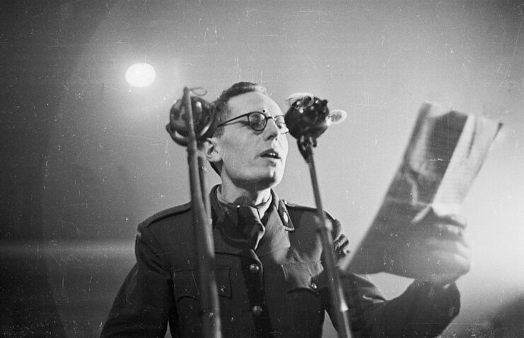 BBC radio announcer reading a script into two microphones