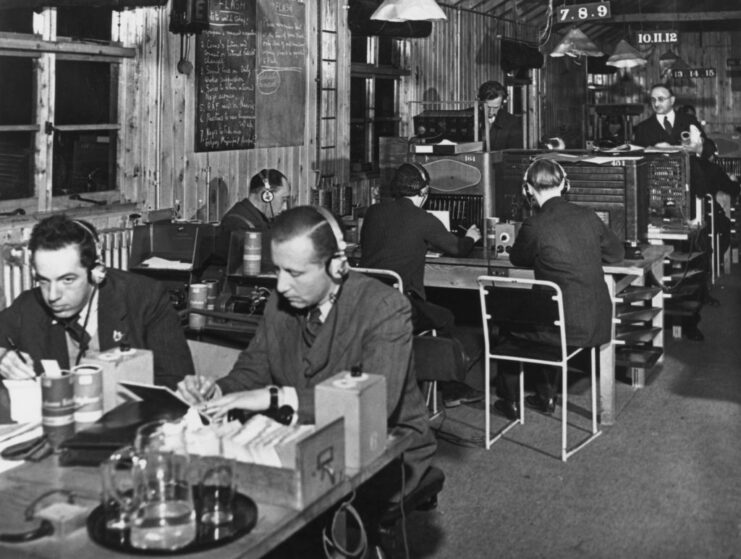 BBC monitoring staff sitting a tables covered in radio equipment