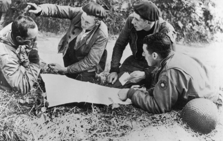 French Resistance members and American servicemen knelt around a map