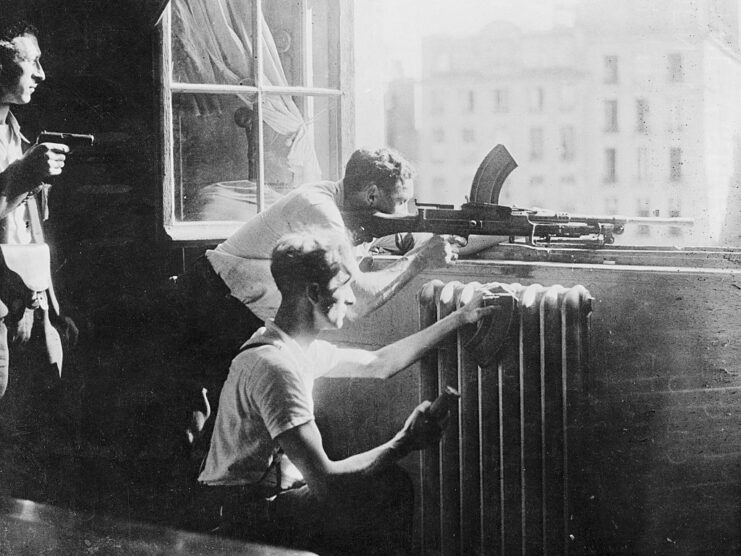 Three French Resistance members aiming weapons out a window