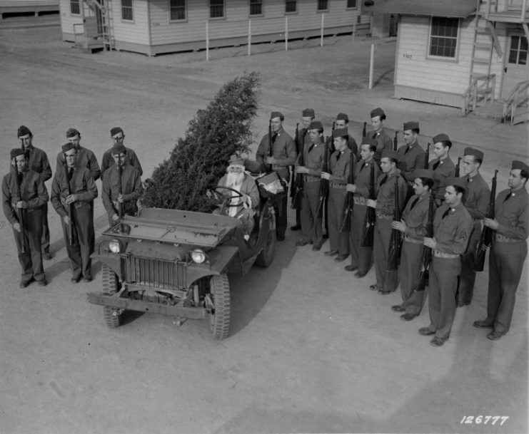 Just before Santa Claus leaves his “jeep-sleigh” the guard of honor stands on each side presenting arms to the Christmas visitor, 1941.