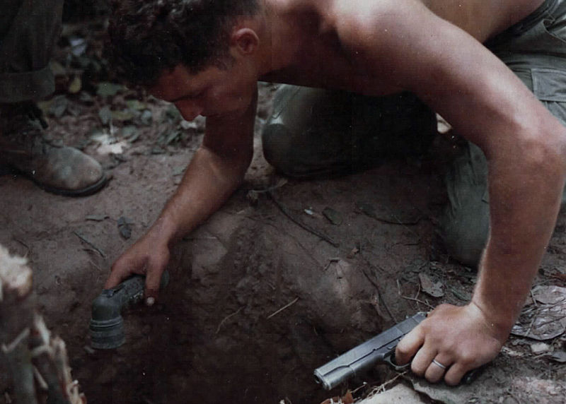 SGT Ronald A. Payne entering a tunnel in search of Viet Cong with a flashlight and M1911 pistol.