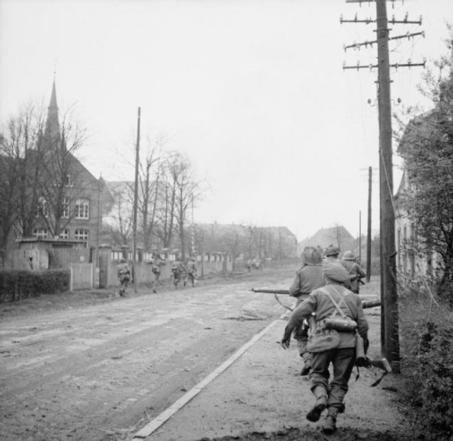 Die britische Armee in Nordwesteuropa 1944–45. Männer der 9. Durham Light Infantry rennen am 29. März 1945 eine Straße in Weseke entlang.