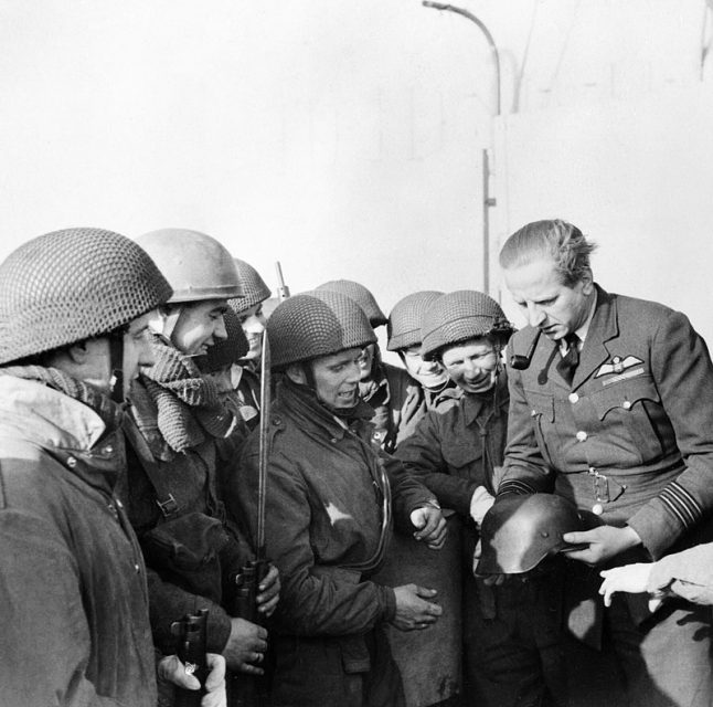 Wing Commander Percy Pickard, CO of No. 51 Squadron RAF, inspects a captured German helmet with troops from 2nd Parachute Battalion after the Bruneval raid, 28 February 1942.
