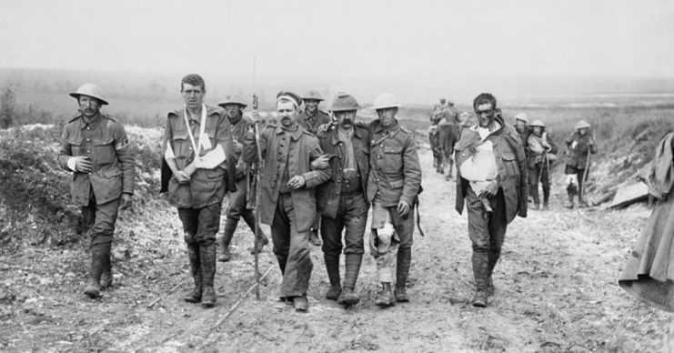 A German prisoner helps British wounded make their way to a dressing station near Bernafay Wood following fighting on Bazentin Ridge, 19 July 1916, during the Battle of the Somme.