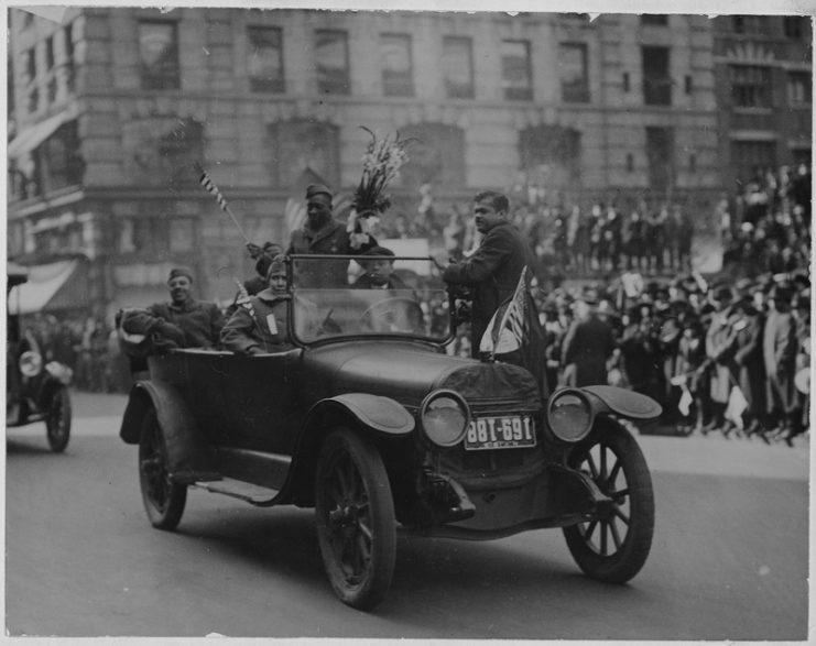 Famous New York [African American] soldiers return home. [Henry] Johnson, one of heroes of New York’s [African American] 369th (old 15th) regiment, passing along Fifth avenue during parade. He is standing in automobile with bouquet presented to him