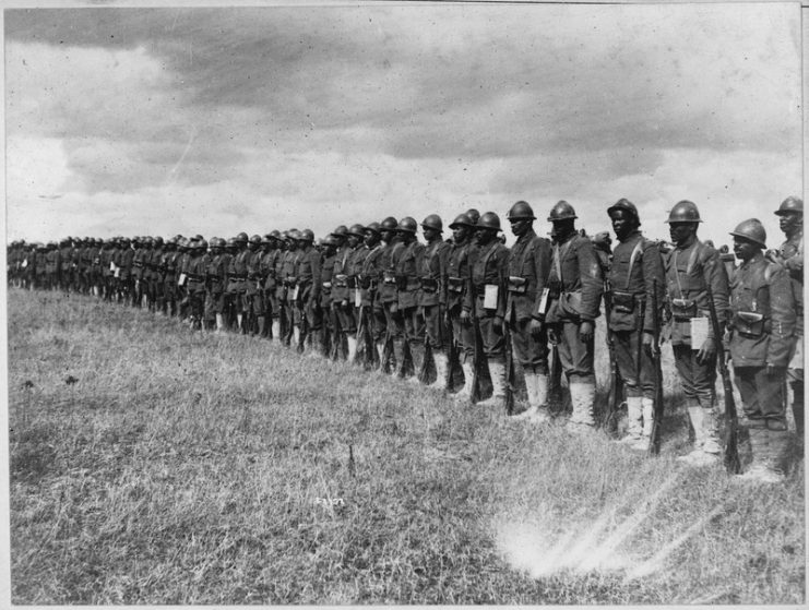 Part of the 15th Regiment Infantry New York National Guard organized by Colonel Haywood, which has been under fire. Two of the men, Privates Johnson and Roberts, displayed exceptional courage while under fire and routed a German raiding party, for which they were decorated with the French Croix de Guerre. It will be noticed that the men have taken to the French helmet, instead of the flatter and broader British style.