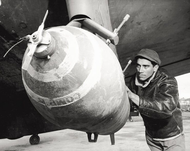 Crewman loading a bomb beneath the wing of a Republic P-47 Thunderbolt