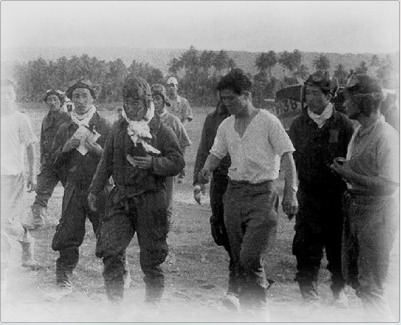 Saburo Sakai (center-left) just after being injured in Guadalcanal and returned to Rabaul. Male with no hat and white shirt in the center-right is Sasai Ruichi. On Sakai’s left is Toshio Ota who has something that seems to be a document.