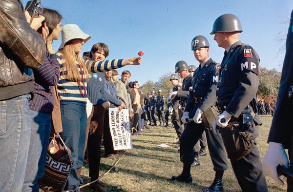 A female demonstrator offers a flower to military police on guard at the Pentagon during an anti-Vietnam demonstration. Arlington, Virginia, USA