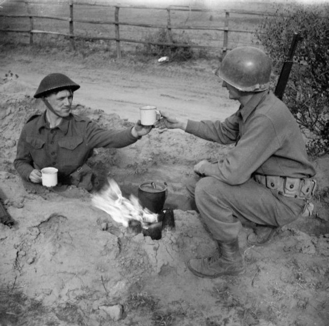 A soldier with the 2/7th Middlesex Regiment shares a cup of tea with an American infantryman in the Anzio bridgehead, February 10, 1944.