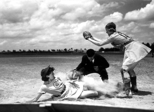 All American Girls Professional Baseball League player Marg Callaghan sliding into home plate as umpire Norris Ward watches.1948