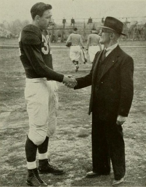 Contemporary Maryland quarterback Tommy Mont shakes hands with William W. Skinner, University of Maryland faculty member and quarterback from the school’s inaugural 1892 football team.