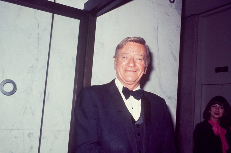 John Wayne standing in a tuxedo