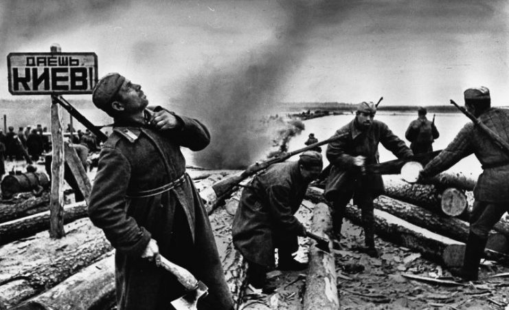 Red Army soldiers working on a pontoon bridge over the Dnieper River. The sign says: “You’ll reach Kiev!”