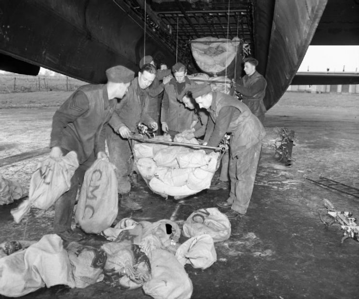 RAF ground crew loading food supplies into slings for hoisting into the bomb bay of an Avro Lancaster heavy bomber of 514 Squadron (1945).
