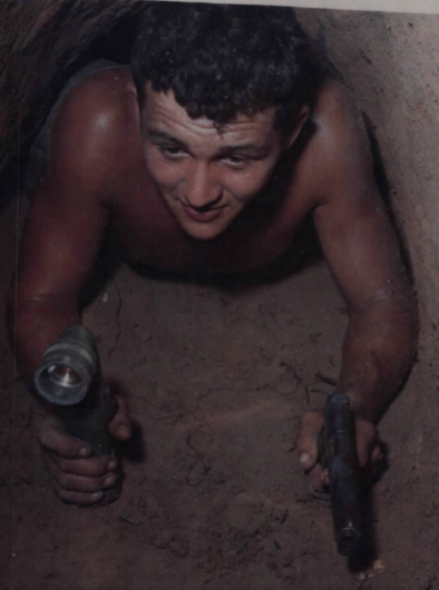 SGT Ronald A. Payne moves through a tunnel in search of Viet Cong with a flashlight and M1911 pistol.