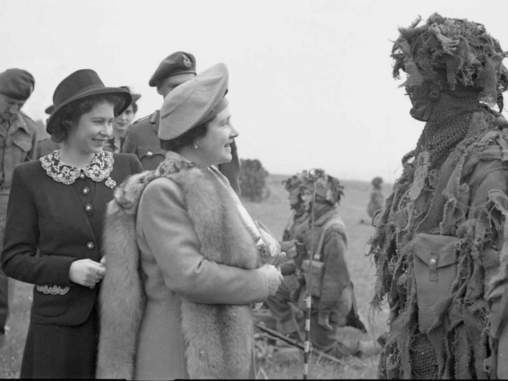 The Queen and Princess Elizabeth talk to a camouflaged sniper during a tour of Airborne forces, 19 May 1944.