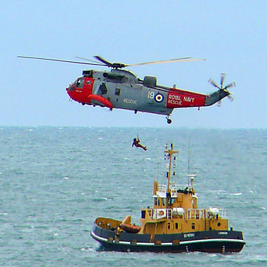 A Royal Navy rescue helicopter in action above a boat