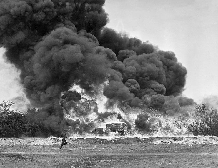 A demonstration of ‘Fougasse’, somewhere in Britain. A car is surrounded in flames and a huge cloud of smoke. c 1940.