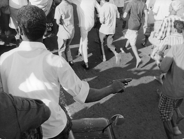 A man holding a pistol in a crowd in Aden, 1967.