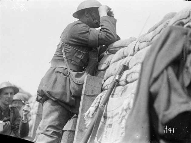 A New Zealand Brigade Commander looks through binoculars at the German position from a front line trench on Hill 63, near Messines, during World War I.