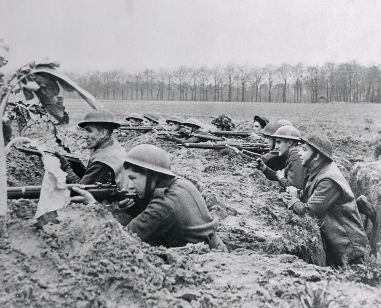 British soldiers aiming their rifles while standing in a trench
