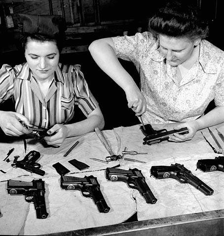 Female workers Agnes Apostle of Dauphin, Manitoba and Joyce Horne of Toronto, Ontario conduct a final assembly of a 9 m.m. semi-automatic pistol destined for China at the John Inglis Co. munitions plant. Toronto, Canada, c. 1943