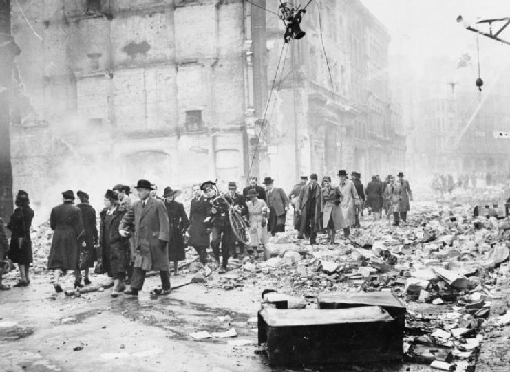 Office workers making their way through debris as they go to work after a heavy air raid on London.