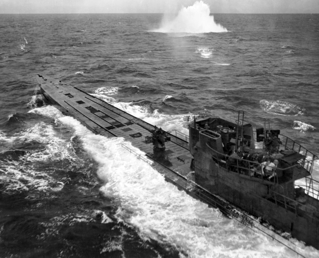 Sailors take cover around the conning tower of a German type IXC submarine under attack from a very low flying aircraft. Atlantic 1943.