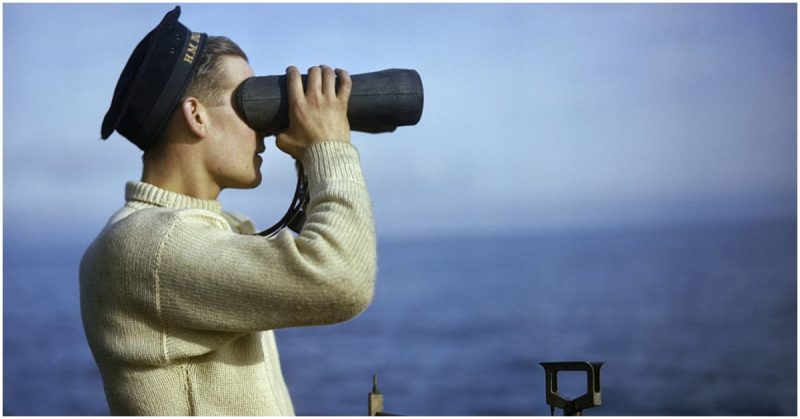 Leading Seaman Walker keeps a look-out from the bridge of HM Submarine TRIBUNE, September 1942. An Asdic rating, Leading Seaman Walker, on the bridge of HMS TRIBUNE keeping a look-out with a torpedo nightsight.