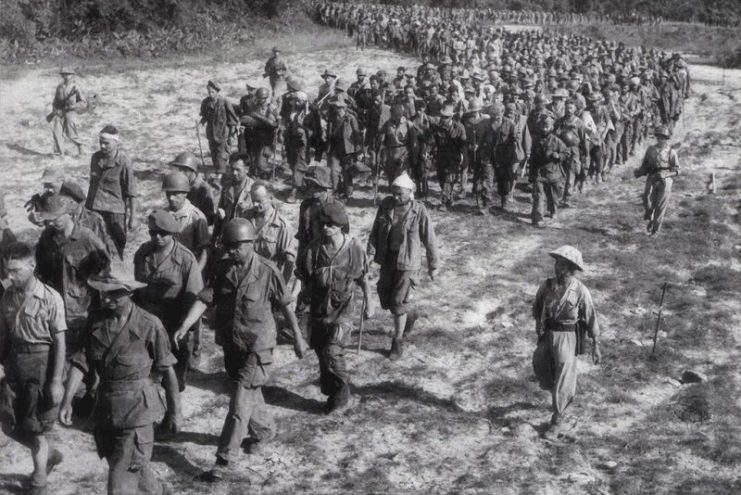 Captured French soldiers from Dien Bien Phu, escorted by Vietnamese troops, walk to a prisoner-of-war camp