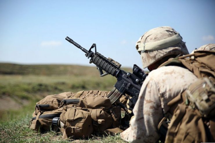 A U.S. Marine adjusts the optics on an M4 carbine