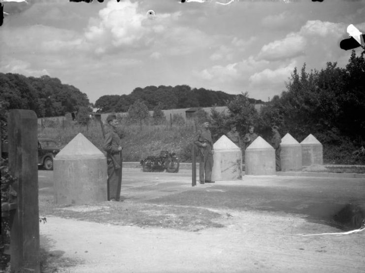 Members of the Local Defence Volunteers (LDV) stand guard at a concrete road barricade at Findon, Sussex, 26 June 1940.