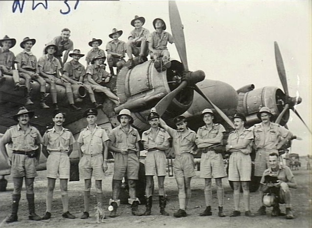 Pilots and observers of No. 31 Squadron RAAF standing on and in front of a Squadron Bristol Beaufighter aircraft. Note the mascots, a Joey (young kangaroo) in front of the group and the dog.