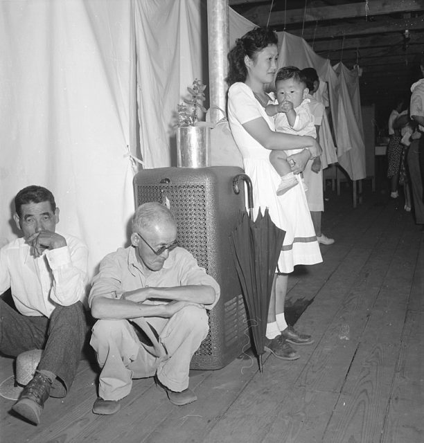 Typical interior scene in a Manzanar barrack apartment. Note the cloth partition separating one apartment from another, lending a small amount of privacy