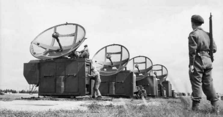 A Royal Air Force Regiment sentry stands guard whilst German technicians assemble captured FuMG 64 “Mannheim” 41 T radar equipment at Grove airfield in Denmark