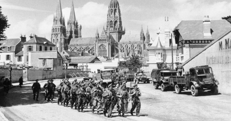 Troops marching through Bayeux, with the cathedral in the background, 27 June 1944.