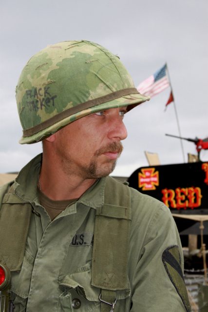 Vietnam Aircavalry soldier ,with stars and stripes behindhim.Re-enactor.