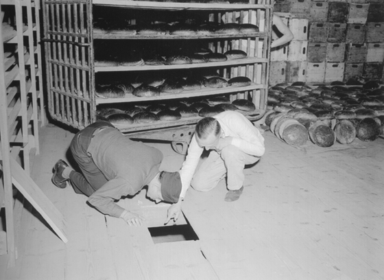 U.S. Lt. Robert R, Rogers, left, and Erich Pinkau, of the German criminal police, inspect the bakery and the hiding place of Leipke Distel, a member of Jewish revenge group Nakam, who had tried to poison loaves of bread for SS prisoners