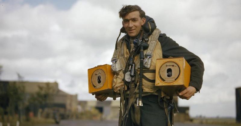 Wireless operator of an Avro Lancaster bomber carrying two pigeon boxes.