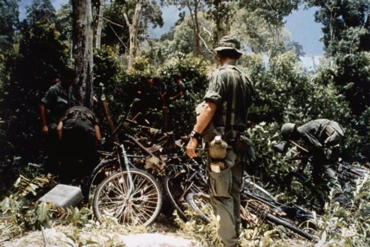 Captain Ramon Costa, S2 Officer for 1 Bn, 27 Infantry Regiment, 25 Infantry Division, US Army, instructs his men on the best method of destroying enemy bicycles and rice found on a search and destroy mission