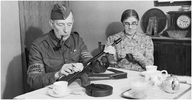  A veteran sergeant in the Dorking Home Guard cleans his Tommy gun at the dining room table, before going on parade, 1 December 1940.