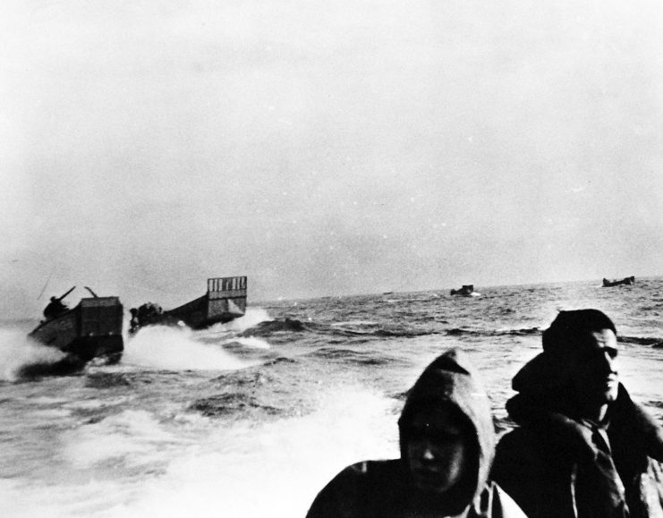 Operation Torch, November 1942. Fedala, French Morocco. U.S. landing barges speed shoreward off Fadala, French Morocco, during landing operations. Note expression of the faces of the two men in the foreground. Fedala is about 15 miles north of Casablanca, the French Moroccan city. U.S. Navy Photograph, released December 3, 1942.