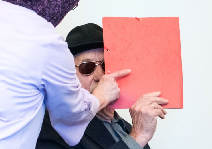 93-year-old former SS guard Bruno Dey covers his face in the courtroom during his trial in Hamburg. GETTY