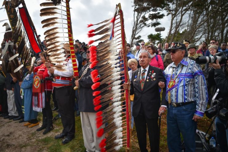 WWII US native American Indian veteran Charles Shay (2R) takes part with others in a ceremony on Omaha Beach in Saint-Laurent-sur-Mer, western France on June 5, 2019, in homage to native American Indians who took part in the DDay landings of World War II. (Photo by LOIC VENANCE / AFP) (Photo credit should read LOIC VENANCE/AFP via Getty Images)