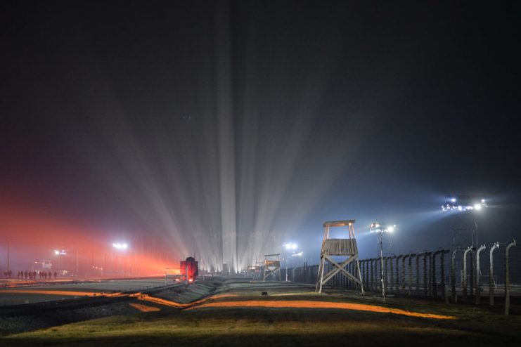 Guard towers and a railway car stand on the illuminated grounds of the former Auschwitz-Birkenau concentration camp during the official ceremony to mark the 75th anniversary of the liberation of the former Nazi-German concentration and extermination camp Auschwitz II – Birkenau. On Monday, January 27, 2020, in Auschwitz II-Birkenau Concentration Camp, Oswiecim, Poland. (Photo by Artur Widak/NurPhoto via Getty Images)